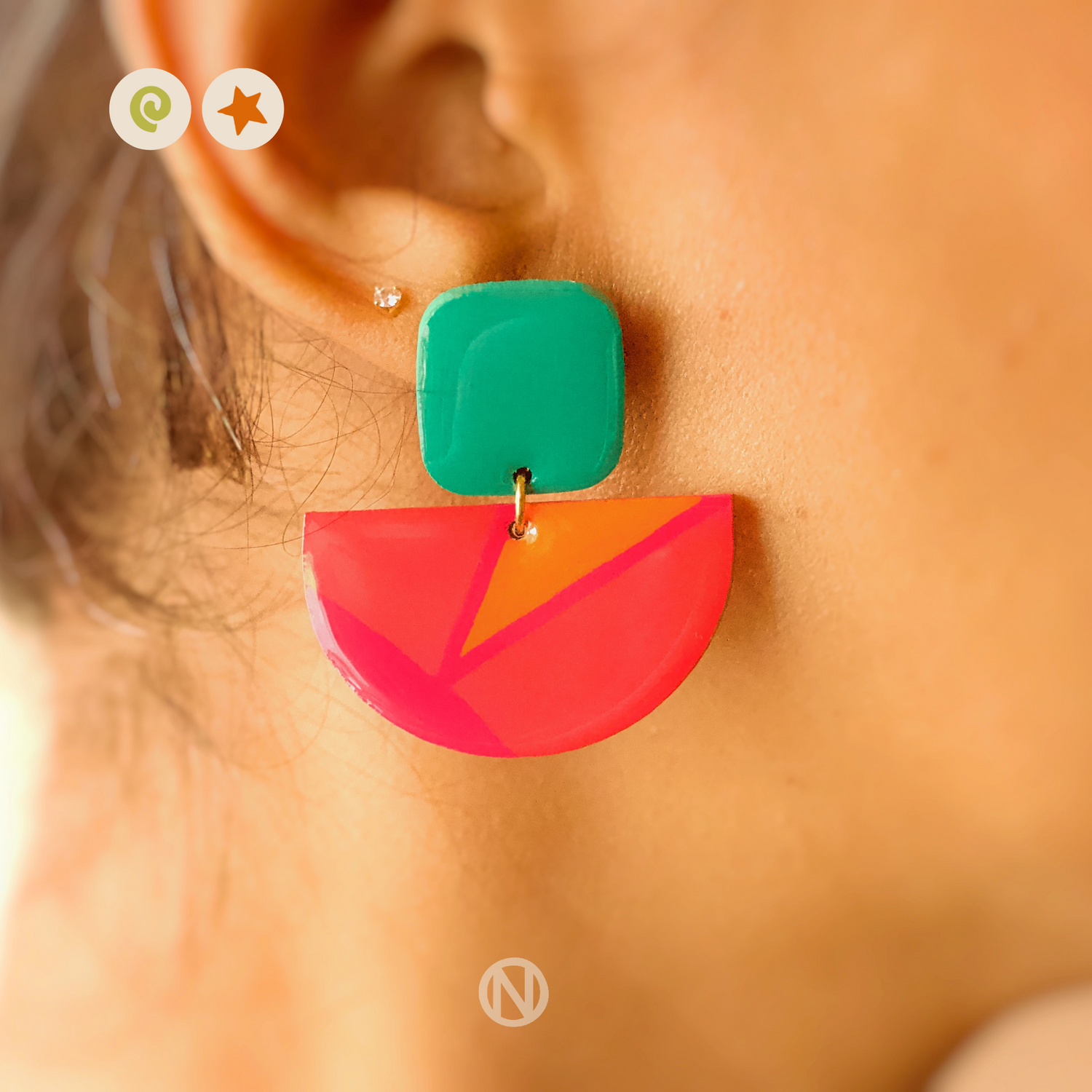 Earrings with a turquoise rounded rectangle shape on top, and a pink and orange semi circle section on the bottom.