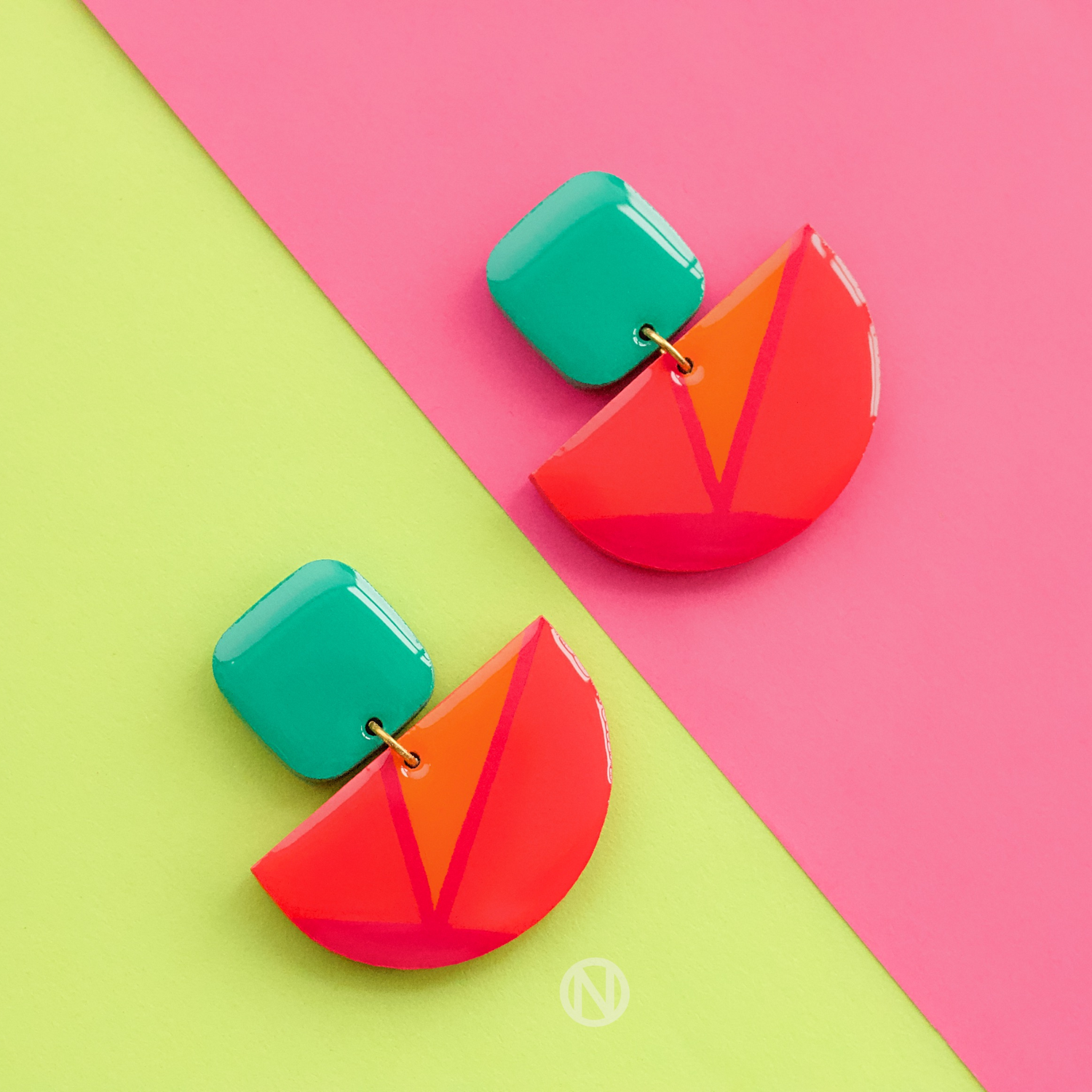 Earrings with a turquoise rounded rectangle shape on top, and a pink and orange semi circle section on the bottom.