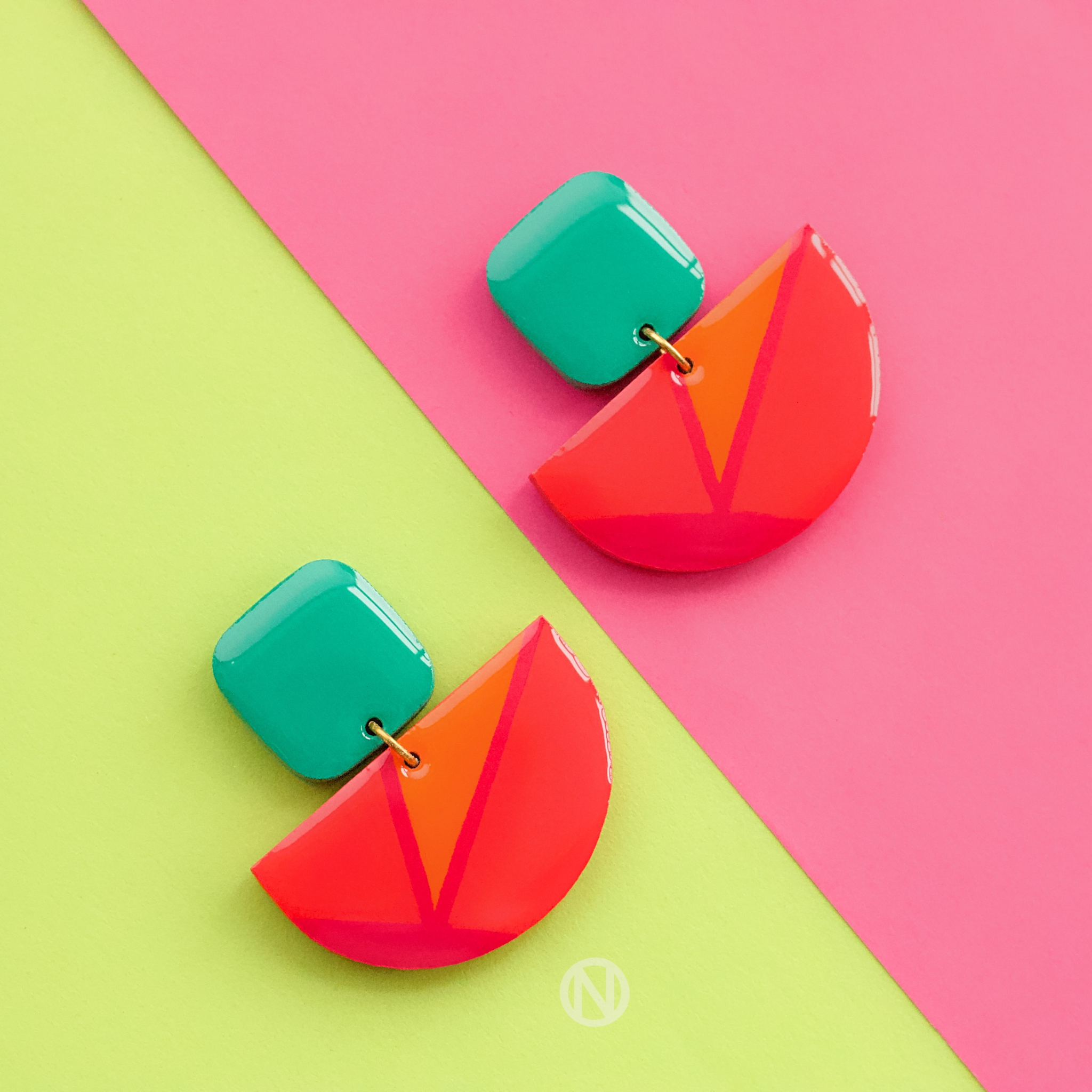Earrings with a turquoise rounded rectangle shape on top, and a pink and orange semi circle section on the bottom.