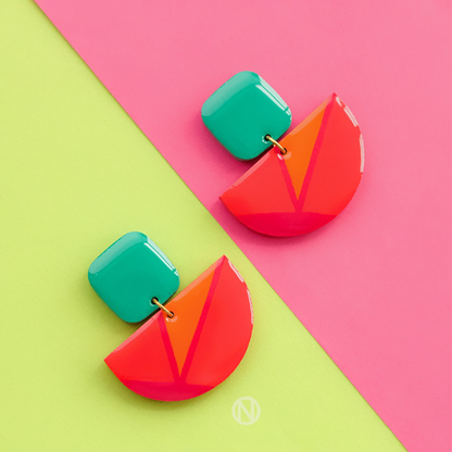 Earrings with a turquoise rounded rectangle shape on top, and a pink and orange semi circle section on the bottom.