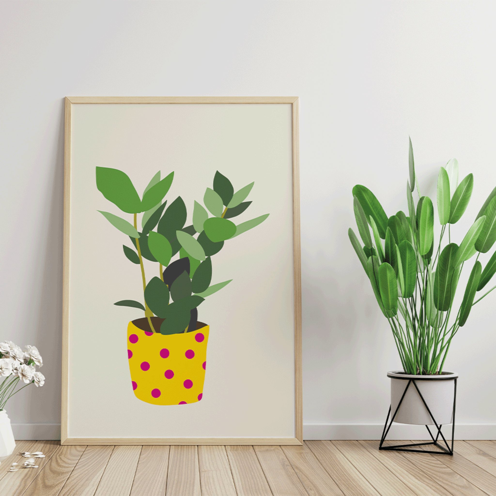 Frame on a white wall next to a plant. The illustration in the frame shows a plant in a yellow pot with pink polka dots.